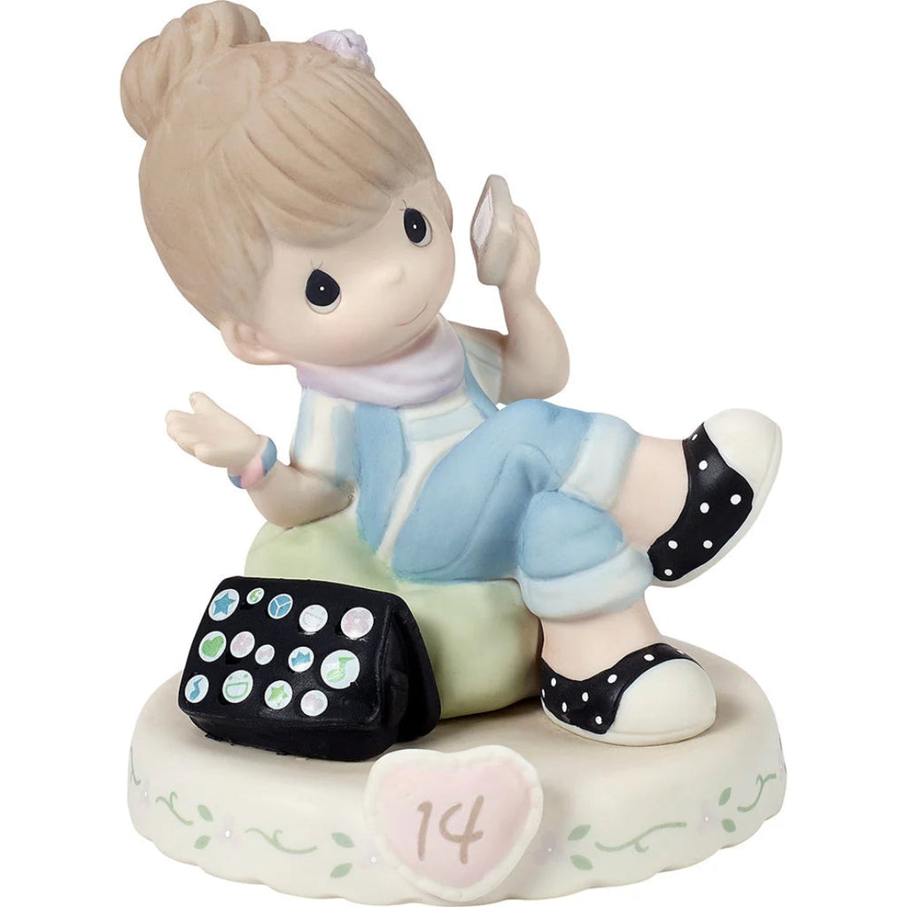 A Precious Moments figurine of a girl with brunette hair in a bun sitting on a  green stool, holding a phone to her ear. She is wearing a light blue and white outfit with black polka-dot shoes with a black polka-dot purse beside her. The figurine is mounted on a round white floral base decorated with a pink heart and the number 14.