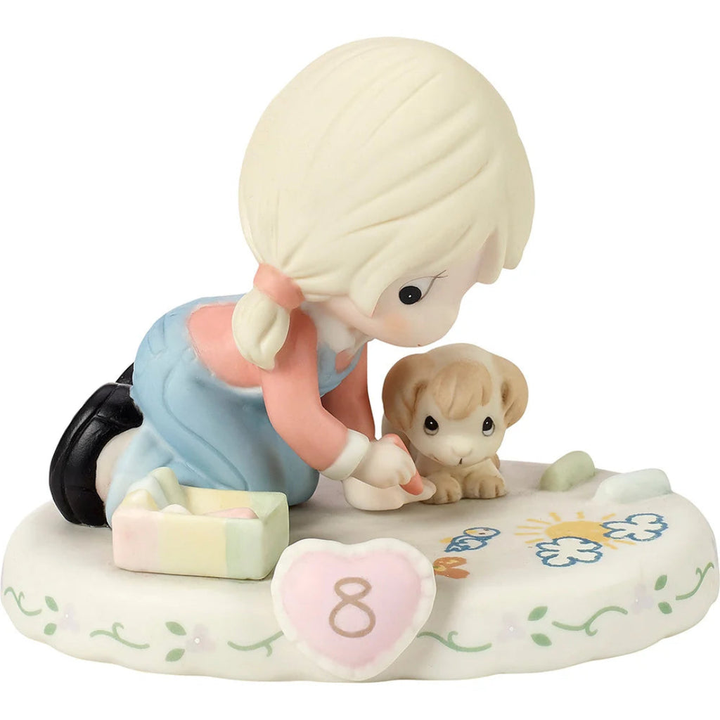 A ceramic figurine of a blonde girl in a blue dress kneeling beside a small tan puppy on a decorated base with a pink heart marked '8'.