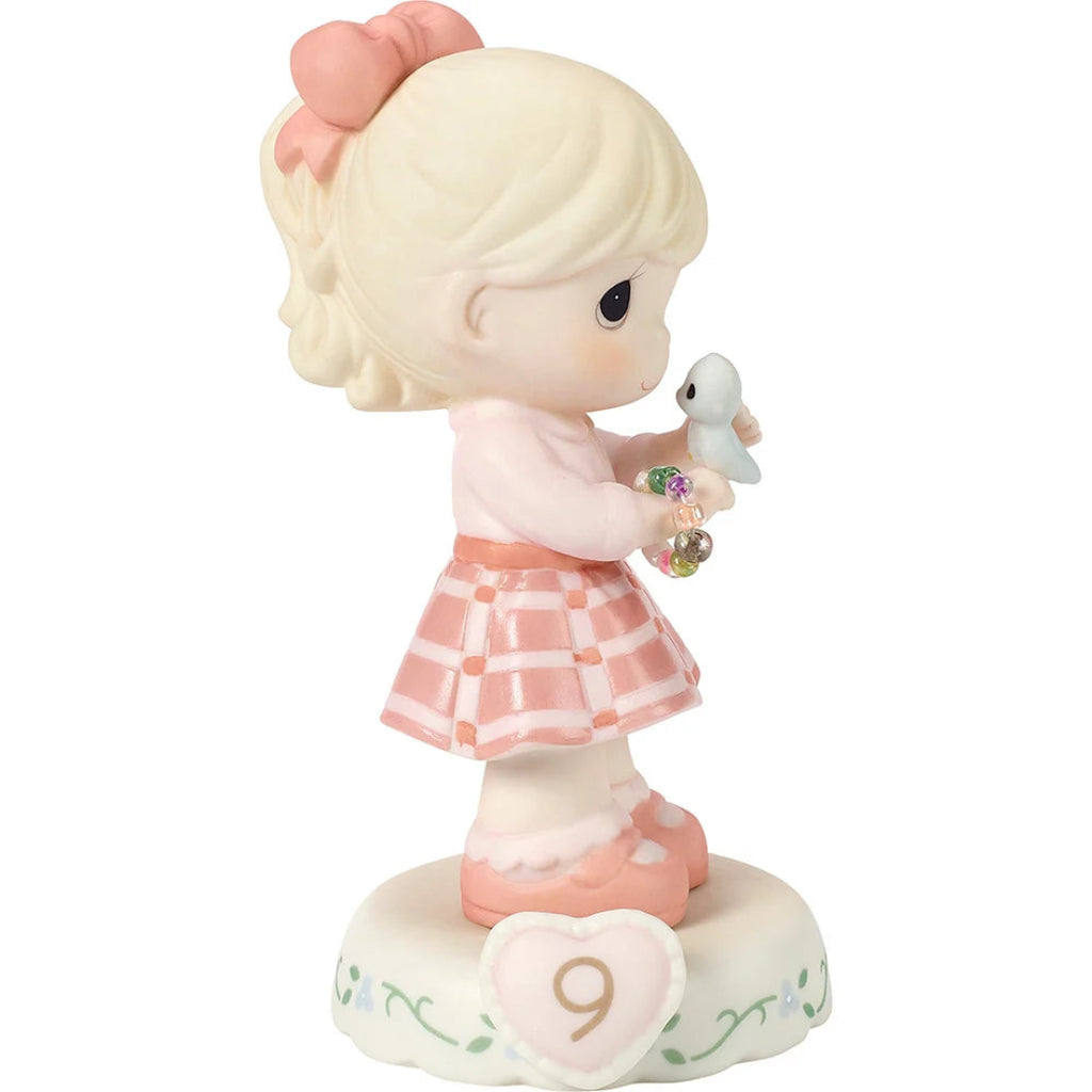 Figurine of a girl holding a bluebird with a heart and number 9 on a white background