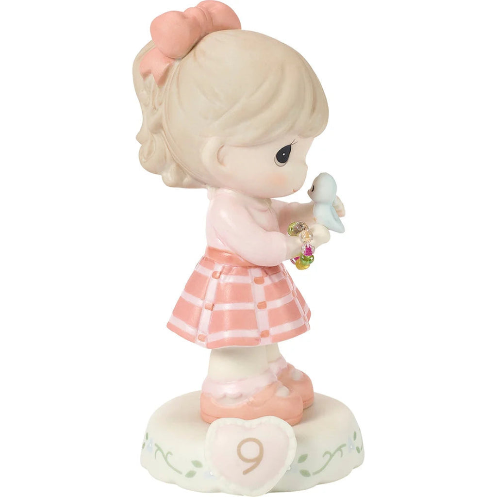 Figurine of a girl holding a bluebird with a heart and number 9 on a white background